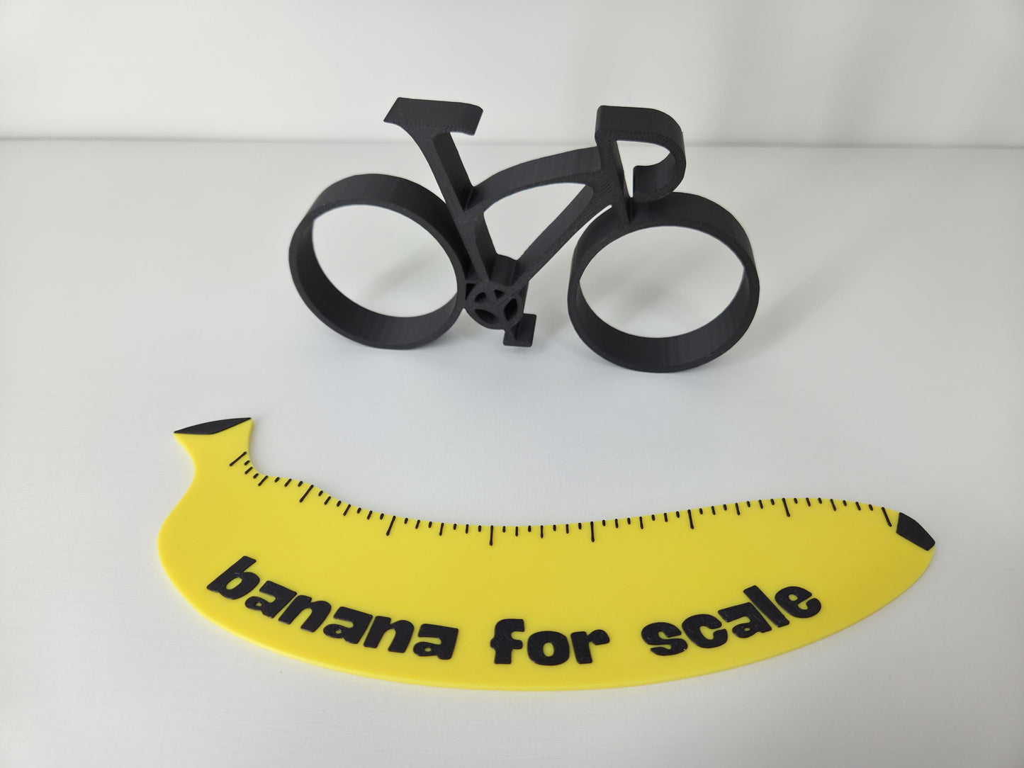 Black bicycle model and yellow banana with 'banana for scale' text on a white background