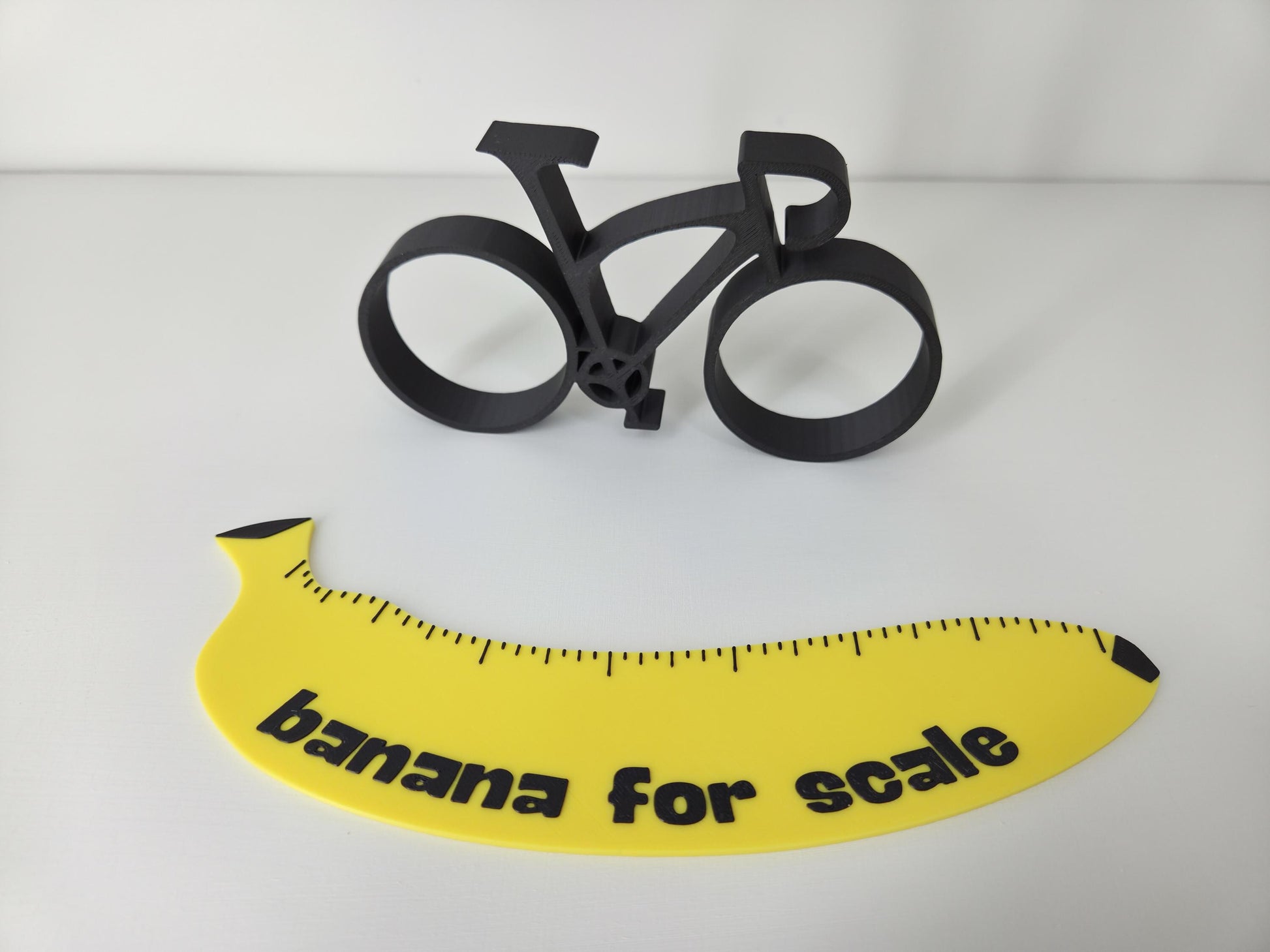 Black bicycle model and yellow banana with 'banana for scale' text on a white background
